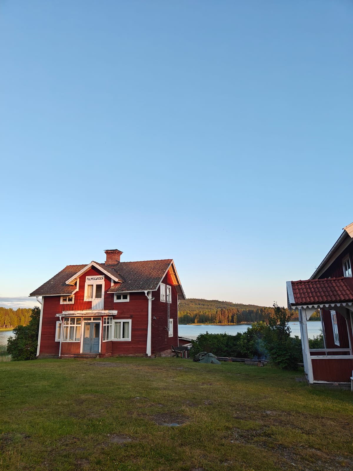 Palmsgården – röd stuga vid Liljan i kvällsljus