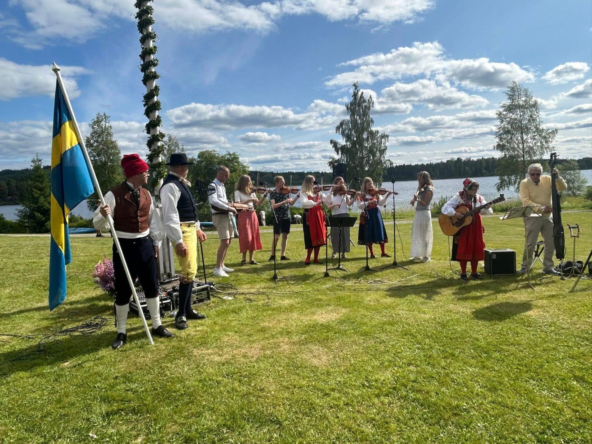 Spelmän i folkdräkt vid midsommarstången på Dalagården